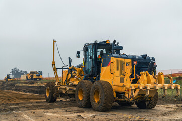 Fototapeta premium Heavy road construction machinery working on infrastructure development site. Industrial vehicles.