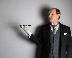 Butler or Formal Waiter in Suit and White Gloves Holding Serving Tray. Professional Hospitality and Courtesy.