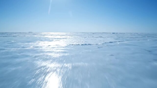 Aerial drone flight over vast frozen ice field under clear blue sky