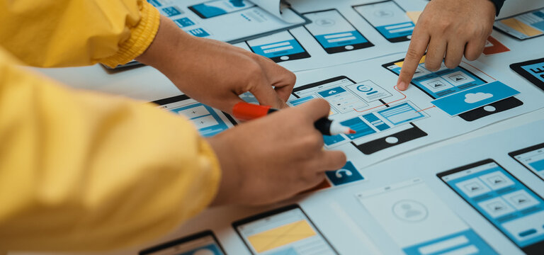 A dynamic creative session showcases hands collaborating on a mobile app design. Colorful sketches and digital elements highlight the innovative development process. SACTR