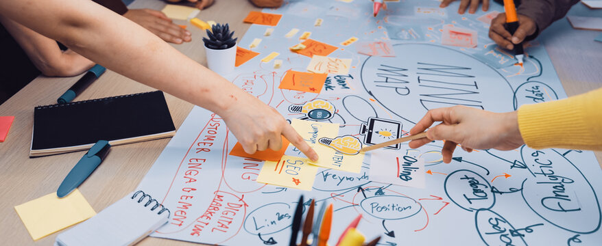 A vibrant scene of a team collaborating on a mind map in a modern office, featuring hands pointing at colorful sticky notes, engaged in dynamic idea generation. SACTR