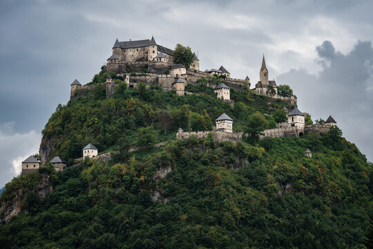 An imposing medieval fortress, Hochosterwitz Castle, sits majestically atop a steep, forested limestone hill.