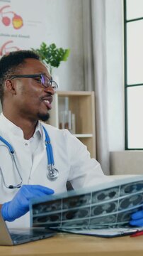 Healthcare and pediatry concept where handsome joyful experienced african american male pediatrician giving high five by 12-aged cheerful boy after revision boy's x-ray scan during his scheduled visit