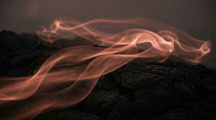 Vibrant orange smoke swirls against a dark background with glowing embers and ash creating a moody abstract scene