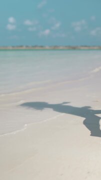 Woman legs barefoot running white sand beach tropical island pov. Slim female feet jogging, leisurely strolling along sea water waves. Relax, travel, summer holiday vacation. Slow motion back view