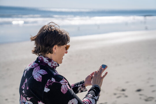 Middle Age wonam using her cell phone at the beach