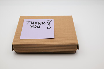 Obraz premium Cardboard box with purple sticky note saying THANK YOU on white background.
