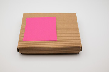 Fototapeta premium Cardboard box with blank pink sticky note on white background.