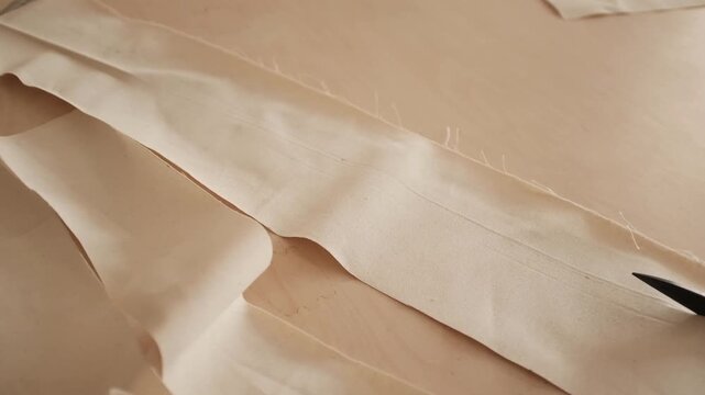Close up of female hands carefully cuts cotton canvas fabric with scissors. Minimal sewing environment, highlighting manual sewing manufacture. Working process in a small business sewing workshop.