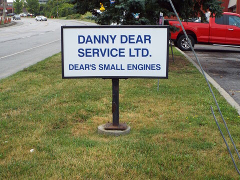 Ottawa, ON, Canada-July 9,2025: A white street-side sign on Industrial Avenue in Ottawa identifies the location of "Danny Dear Service Ltd. and Dear&rsquo;s Small Engines."