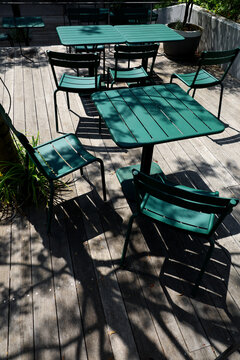 Dappled sunlight on the wooden deck and a green table set