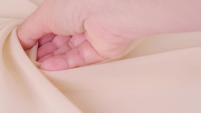 Female hands inspecting silk texture and quality delicate chiffon, crepe, hand feels sensual tactile pleasure, testing for durability, stretch and crease resistance