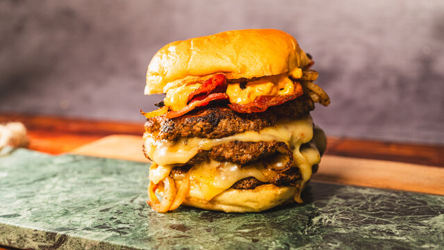 Massive triple patty smash burger with crispy bacon, homemade sauce, and onions. Juicy, indulgent, and stacked high. Perfect for gourmet fast food lovers and hearty meals.