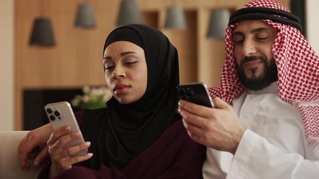 Modern Arab couple using smartphones together while spending quality time