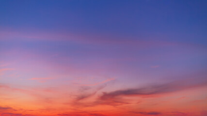 Obraz premium Stunning sunset sky with dramatic purple and orange clouds at twilight,A breathtaking panoramic view of a vibrant sunset sky, featuring a gradient of deep purple, soft pink, and fiery orange clouds.