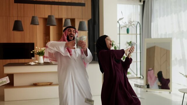 Wealthy Muslim couple in traditional clothing throwing money, profit success