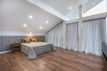 A spacious bedroom in the attic of a luxurious mansion. Panoramic Windows, bright interior decor.