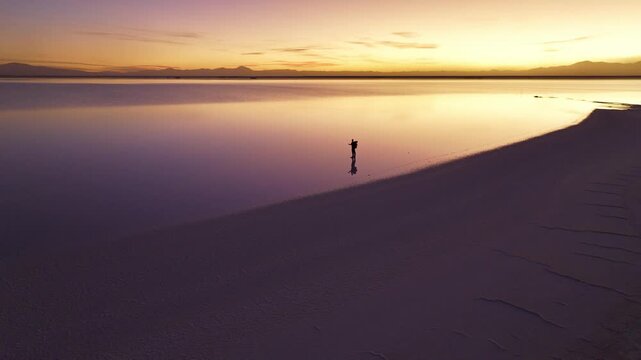 Man standing at Salinas Grandes during sunset