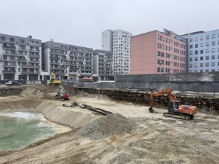 excavation in a metropolitan area, featuring multiple construction vehicles operating inside a...