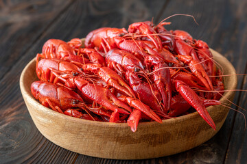 Wooden bowl of bright red boiled crawfish, rustic table