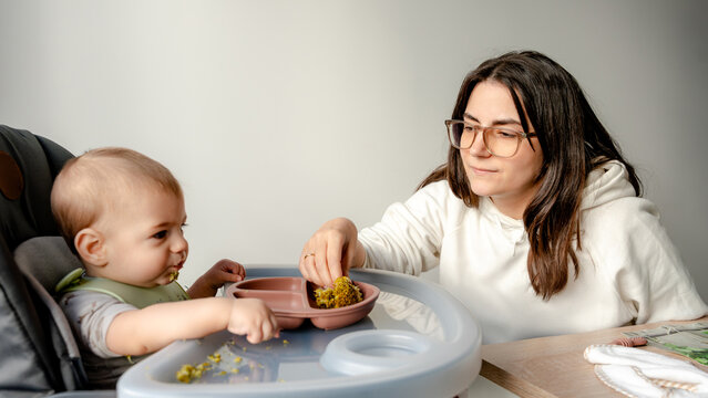 Baby enjoying led weaning with parent assistance
