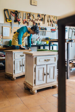 Woman working in a restoration workshop with furniture