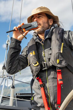 Sailor with radio communicating on a sailing boat