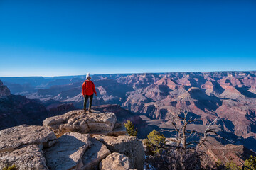 A woman stands on a rock overlooking a beautiful landscape