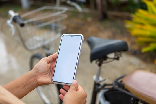 Woman holding smartphone near a bicycle