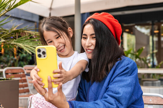 Mother and daughter taking a selfie at a cafe