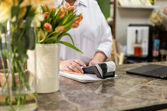 Counter in a small flower shop, card payment terminal and a laptop