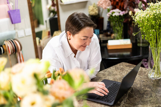 Florist working online in vibrant flower shop