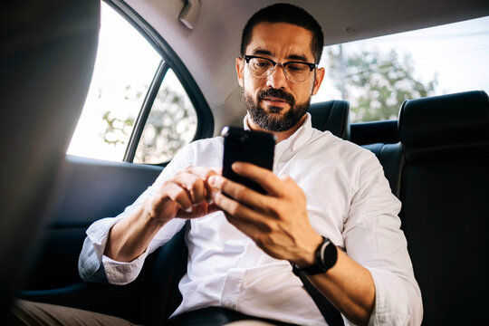 Business man using smartphone while commuting in car
