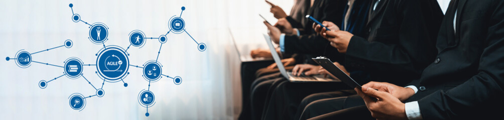 A group of business professionals in formal attire using modern technology, showcasing smartphones and laptops while highlighting the importance of digital interaction in the workplace. Amity