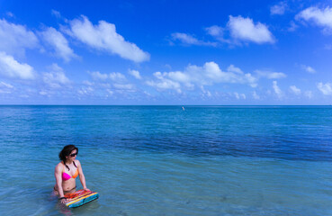 Fototapeta premium A woman is sitting on a surfboard in the ocean