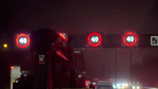 Night view of smart motorway gantries with speed cameras and 40 mph variable limit signs