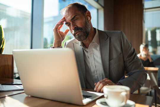 Stressed businessman working on laptop at coffee shop