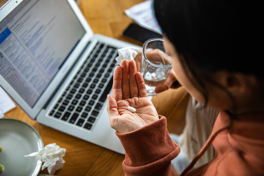 Person taking medicine while working at home desk