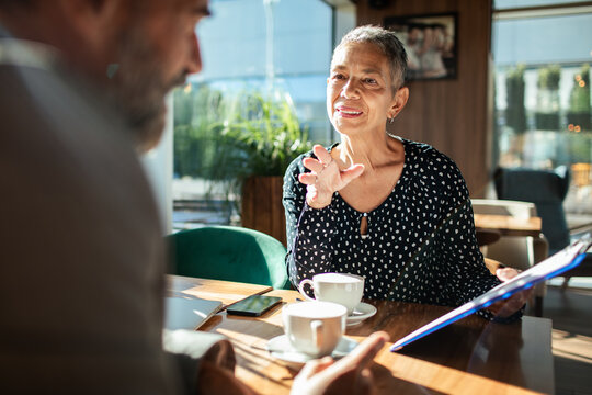 Senior woman discussing business with colleague at cafe