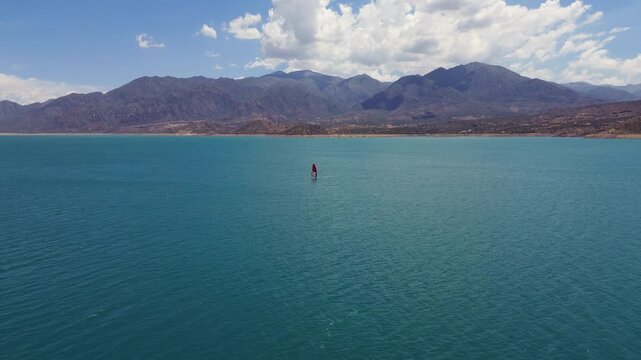 Aerial shot of a man windsurfing on Lake Potrerillos in Mendoza, Argentina