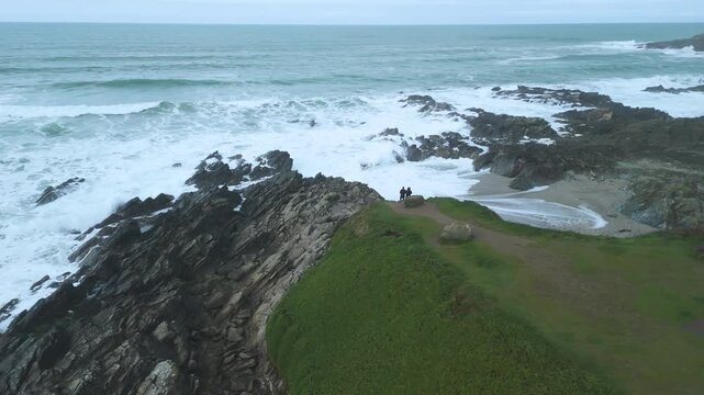 drone shot of tourists looking out from headland North Fistral beach at cornwall cliffs at newguay