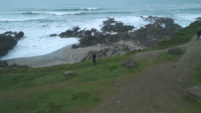 drone shot of tourists looking out from headland North Fistral beach at cornwall cliffs at newguay 