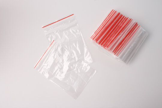 Transparent plastic zip lock bags with red sealing strips on white background. Flat lay composition. Packaging and storage supplies concept for design. Minimal layout with copy space