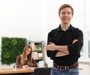 Fototapeta premium Portrait of smiling recruiter with crossed arms and candidate in office, selective focus. Space for text