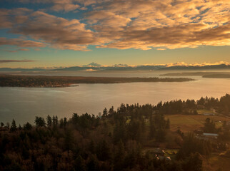 Fototapeta premium Aerial view of Lummi island and Hale Passage with Mt. Baker and the Twin Sisters Mountains in the background. Dramatic sunrise in the Puget Sound area of western Washington state.