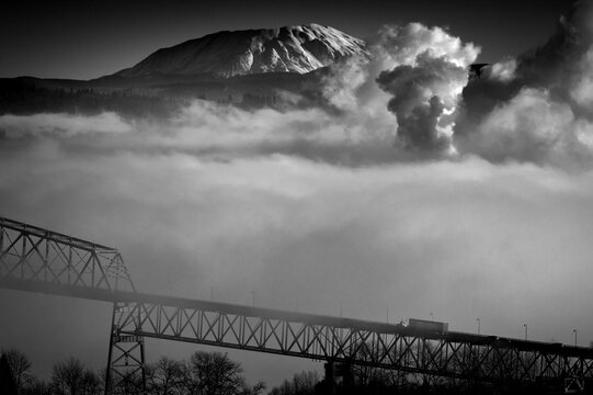 Lewis and Clark Bridge, spanning the Columbia River, shrouded in fog with the volcanic Mt. St. Helens in the background. This bridge brings travelers from Longview, Washington to Rainier, Oregon.