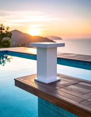 Modern white pedestal by pool, scenic sunset over ocean and mountains