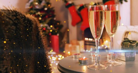 Showing two filled champagne flutes on round table by fireplace, with candles, gift, copy space