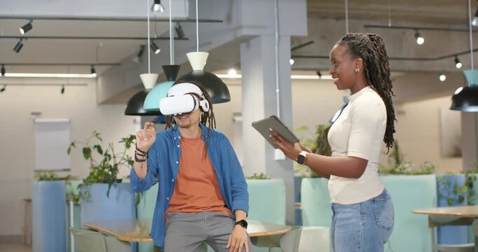 African American team running VR usability test with man donning headset while woman tapping tablet