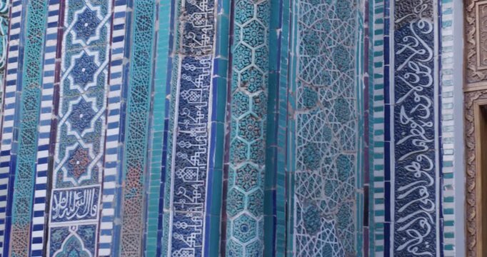 Decorative panel of blue and turquoise Islamic ceramic tiles featuring intricate geometric ornamentation. Close-up of traditional mosaic pattern on historic architectural surface.